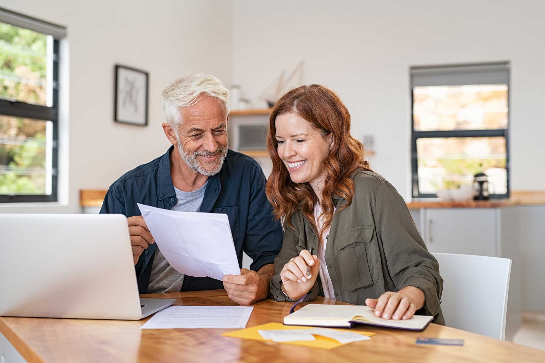 A couple sitting at the table looking at documents.